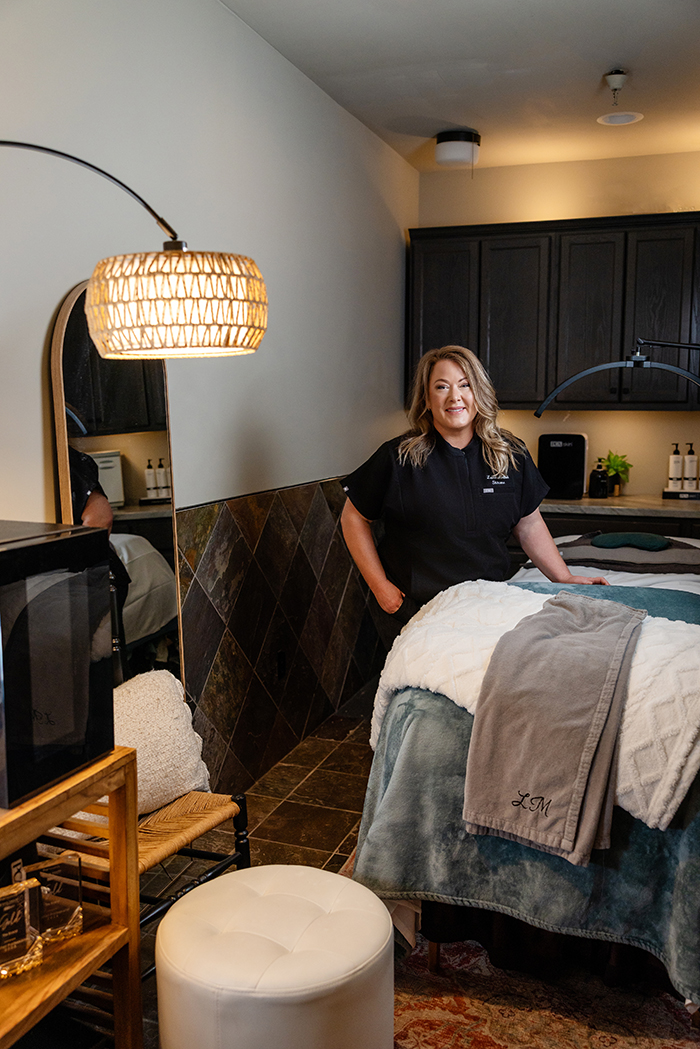 Premium-Skincare-Esthetician-Services-in-Columbia-Missouri Laura poses beside the private space dedicated to skincare and esthetician services inside The Strand Salon and Spa in Columbia, MO.
